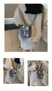 Detailed view of grey crossbody phone bag with multi-colored heart patches and shoulder strap
