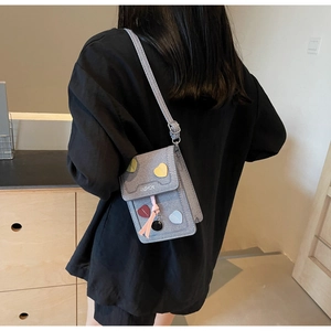 Detail of a vintage-style canvas crossbody phone bag with 3D colorful heart patches