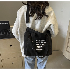 Détail du sac cabas en toile noire avec texte imprimé sur un sweat à capuche