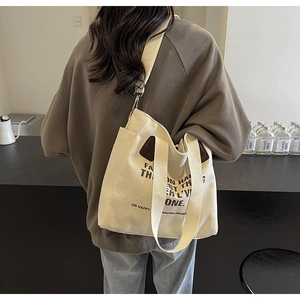 Détail du sac cabas en toile blanc cassé avec poignées en cuir et bandoulière réglable