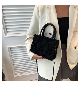 Detail einer schwarzen gesteppten Tweed-Handtasche mit Fransen und runden Griffen