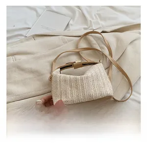 Détail du sac à main en paille tressée crème avec base en cuir kaki et boucle dorée