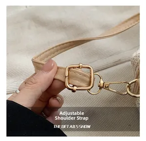 Détail de la bandoulière en cuir réglable avec boucle dorée sur un sac en paille