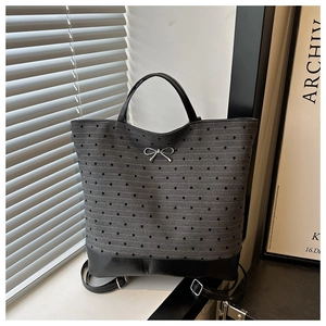 Detail of grey striped bag with black heart dots and silver metal bow on a windowsill