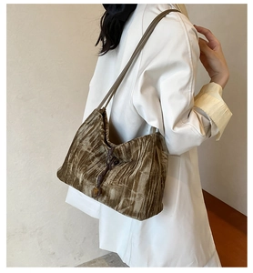 Detailed view of brown velvet pleated tote bag with drawstring and amber bead on a model
