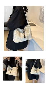 Detail of cream pleated fabric shoulder bag with unique brown knot and metal charms