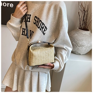 Détail du sac à main en paille tressée avec bordure en cuir noir et fermoir doré