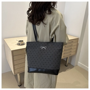 Detail of dark grey polka dot tote bag with a white bow and black leather base