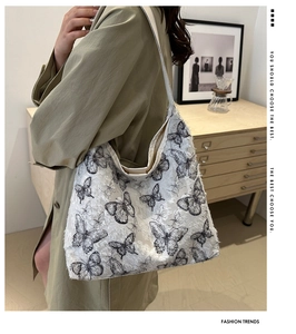 Detailed view of women's tote bag with black butterfly prints and lace texture