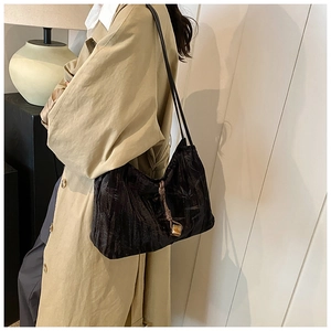 Detail of black pleated shoulder bag with decorative knotted charm and gold hardware