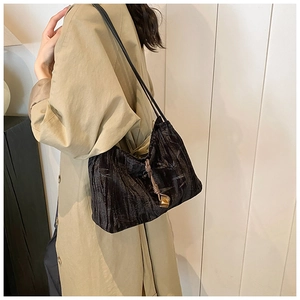 Detail of a black pleated velvet hobo bag featuring knot details and gold metal pendants