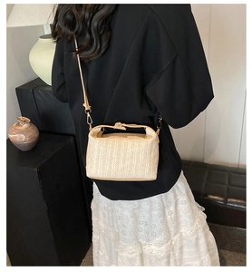Détail d'un sac bandoulière en paille tissée avec boucle métallique et texture beige