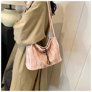 Detail of light pink suede tote bag featuring floral textures and retro drawstring closure