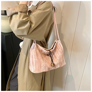 Pink velvet tote bag with bamboo leaf pattern and drawstring closure shown with trench coat