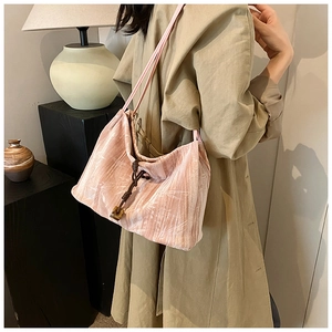 Detail view of pink pleated tote bag with drawstring and beads on beige trench coat