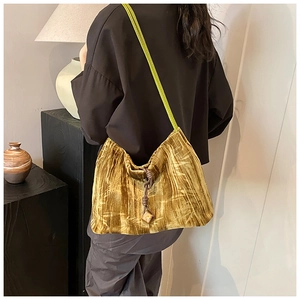 Detail of suede shoulder bag with bamboo leaf pattern and green strap on a model