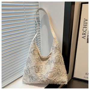 Detailed close-up of butterfly embroidery and distressed fringe on the canvas hobo bag
