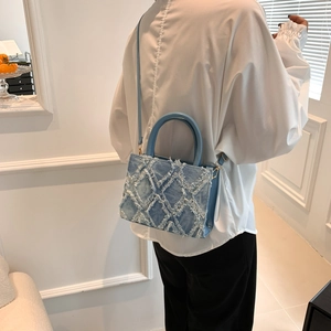 Detail of light blue denim tote bag featuring quilted pattern and frayed edge design