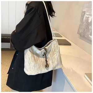 Detail view of the champagne gold velvet pleated tote bag with bamboo leaf pattern