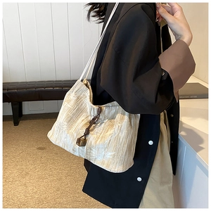Detail of beige textured fabric tote with drawstring closure and decorative pendant