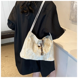 Detailed view of beige textured tote bag featuring thin white ropes and brown tassels