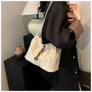Detail of beige pleated fabric shoulder bag with drawstring closure and square pendant