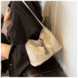 Detail view of beige pleated shoulder bag with amber resin pendant and drawstring