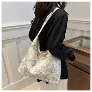Close-up of fuzzy white tote bag featuring gray butterfly prints and long fringe texture