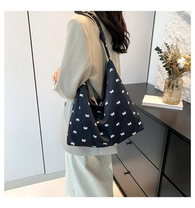 Chic black canvas hobo bag with white bow prints and stylish knotted shoulder strap