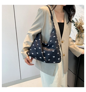 Detail of black tote bag with white bow prints and stylish knotted shoulder strap
