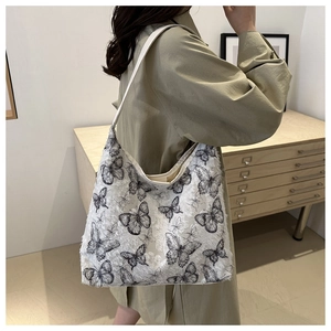 Close-up of butterfly print canvas tote bag with fringed edges and slim shoulder straps