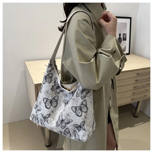 Detailed shot of large butterfly tote bag with fringe texture on a khaki trench coat
