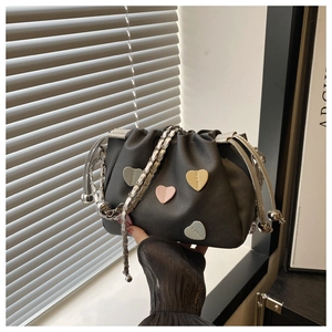 Detail of black pleated bucket bag with pastel heart patches and silver chain strap