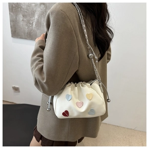 Detail of cream puff bucket bag with colorful heart patches and chain strap