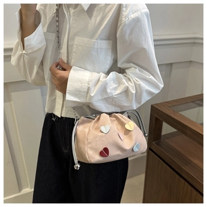 Close-up of pink cloud bucket bag with colorful heart charms and silver chain strap