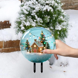 Nahaufnahme von Weihnachts-Lebkuchenhaus-Kristallkugel-Gartenstecker mit warmen LED-Lichtern