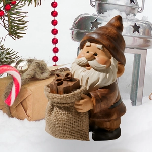 Detail of Christmas gnome figurine with gift bag in a festive winter garden setting