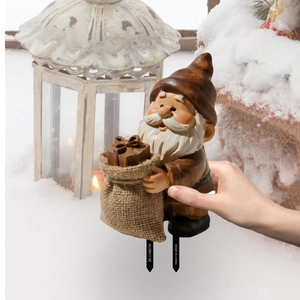 Detail of a resin Christmas gnome garden stake with wood-grain texture in a snowy setting