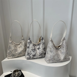 Chic butterfly embroidered canvas tote bags displayed on a sleek white podium stand