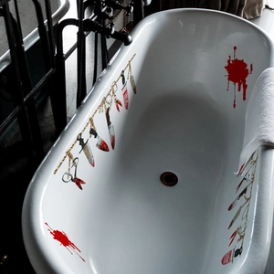 Halloween bloody weapon stickers on white bathtub with hanging knife and blood splatter design
