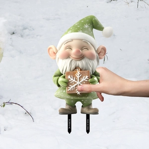 Green Christmas gnome garden stake being inserted into snowy ground for winter decor