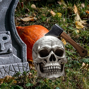 Halloween skull garden stake decoration with axe in head and outdoor lawn graveyard scene