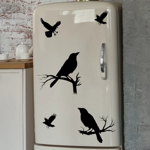 Close-up of black crow silhouette wall stickers on a vintage beige refrigerator