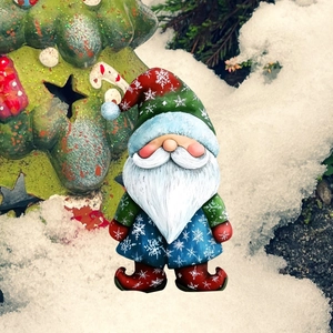 Vue détaillée d'une statue de nain de Noël dans la neige avec bonnet rouge et manteau bleu