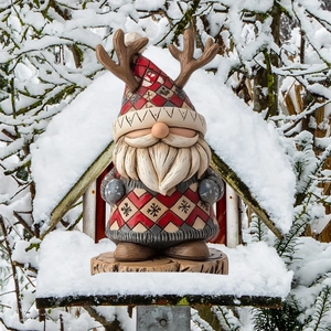 Nain de jardin de Noël avec bonnet à bois de cerf et sac cadeau sur la neige