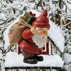 Détail d'un gnome de Noël en bois avec sac de cadeaux dans un jardin enneigé