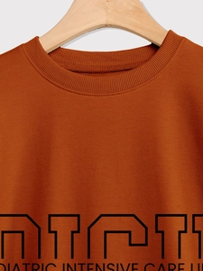 Detail of the ribbed crewneck and black PICU pediatric print on the orange sweatshirt