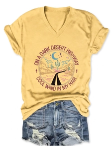 Flat lay of yellow V-neck T-shirt with desert graphic and distressed denim shorts