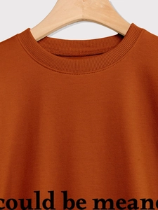 Detail of ribbed crewneck and black letter print on burnt orange cotton sweatshirt