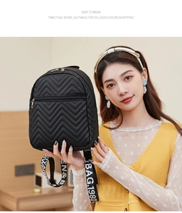 Detail of wave quilted black mini backpack with letter printed straps and metal zipper